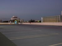 a picture of an empty parking lot with cars parked outside of it with building lights in the background