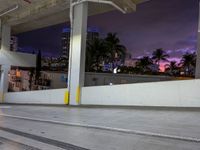 a skateboard parked under a high rise building next to a road with buildings and palm trees