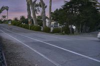 an empty street with a sign indicating to stop traffic in front of some houses at sunset