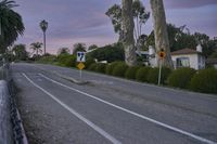 an empty street with a sign indicating to stop traffic in front of some houses at sunset