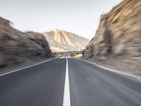 a highway in a mountain with mountains in the background with a blurry photo of the road