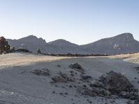 a view of a large rock formation with a person walking up the hill to it