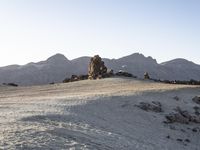 a view of a large rock formation with a person walking up the hill to it