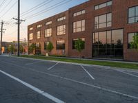 an empty street in front of a large red brick building on the other side of the road is a street light that has a line for motorists