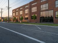 an empty street in front of a large red brick building on the other side of the road is a street light that has a line for motorists