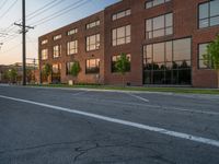 an empty street in front of a large red brick building on the other side of the road is a street light that has a line for motorists