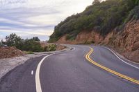 the empty roadway is lined with rocks and rock wall that provide a winding, scenic view