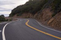 the empty roadway is lined with rocks and rock wall that provide a winding, scenic view