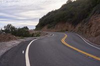 the empty roadway is lined with rocks and rock wall that provide a winding, scenic view