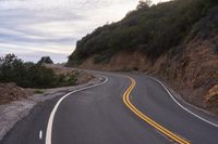 the empty roadway is lined with rocks and rock wall that provide a winding, scenic view