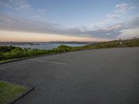 the parking lot by the water at dusk is empty and ready to be used for skateboard