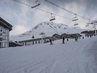 people skiing down a snowy slope at the base of a ski lift at the resort