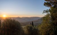 the sun is rising in the distance with a scenic view of the countryside and hills