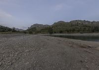 the mountains in the distance are filled with trees and rocks and a river bank is empty