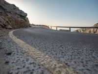 a highway on the side of a rocky hill in europe and on the far side there are bridges