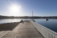 the sun is shining over the bay and a dock on the water's edge