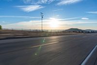 a motorcycle riding along a highway at sunset with mountain in the background, with blue sky