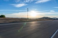 a motorcycle riding along a highway at sunset with mountain in the background, with blue sky