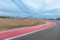 a photo of a dirt race track with sun setting in the distance of the track