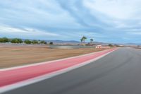 a photo of a dirt race track with sun setting in the distance of the track