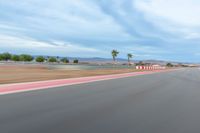 a photo of a dirt race track with sun setting in the distance of the track