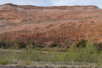 the area has red rocks, green plants and some trees in it, which is the color of red