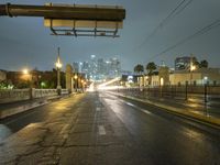 an empty road with traffic on both sides during night time with the city light glowing on the building