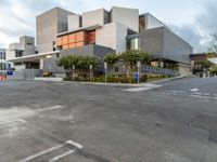 the building is in a large parking lot next to a large parking lot with cars and trees