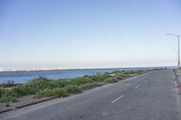 empty road going along a beach next to a body of water on a clear day