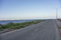 empty road going along a beach next to a body of water on a clear day