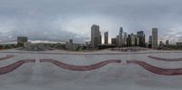 a skateboarder in the air over a cement bowl with a city skyline in the background