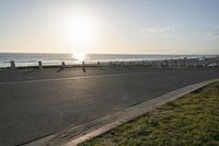 an empty road near a beach and waves as well as cars on the sand and houses on the beach