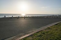 an empty road near a beach and waves as well as cars on the sand and houses on the beach