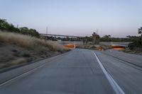 the view of an empty highway from a moving car windshield and back going toward a bridge