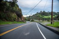 a narrow road with many yellow traffic signs and trees in the background on a cloudy day