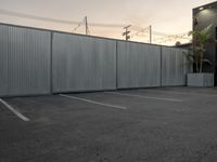 a street is seen through a wall near a building and a car parking lot,