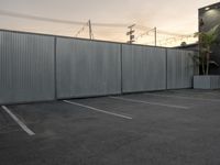 a street is seen through a wall near a building and a car parking lot,