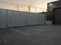 a street is seen through a wall near a building and a car parking lot,