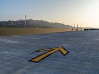 a yellow arrow marks a parking area outside of a building with a mountain behind it