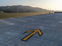 a yellow arrow marks a parking area outside of a building with a mountain behind it