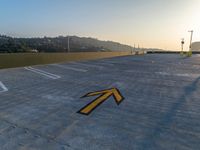 a yellow arrow marks a parking area outside of a building with a mountain behind it