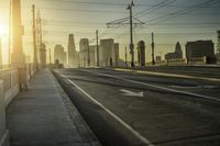 an empty highway with power lines leading to city buildings in the back ground and road tracks