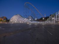 a row of wooden coaster coasters that are outside at night near some roller coaster coasters