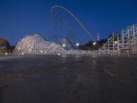 a row of wooden coaster coasters that are outside at night near some roller coaster coasters