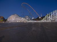 a row of wooden coaster coasters that are outside at night near some roller coaster coasters