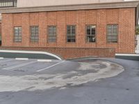 two men in suits are skateboarding on a cement surface in a building parking lot