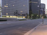 the empty street has a lot of lights on it at dusk in a large city