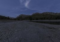 the night time view shows the low water levels on a riverbed with trees on both sides