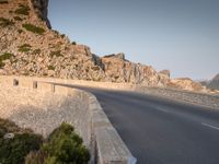 a road with rocks at the edge is next to a mountain with no cars on it