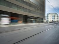 the motion blurs off a moving train on tracks in a big city street, and the buildings are also blurred